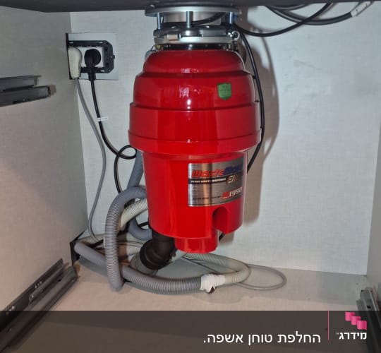 מגרסת אשפה אדומה מתחת לכיור עם צינורות חשמל